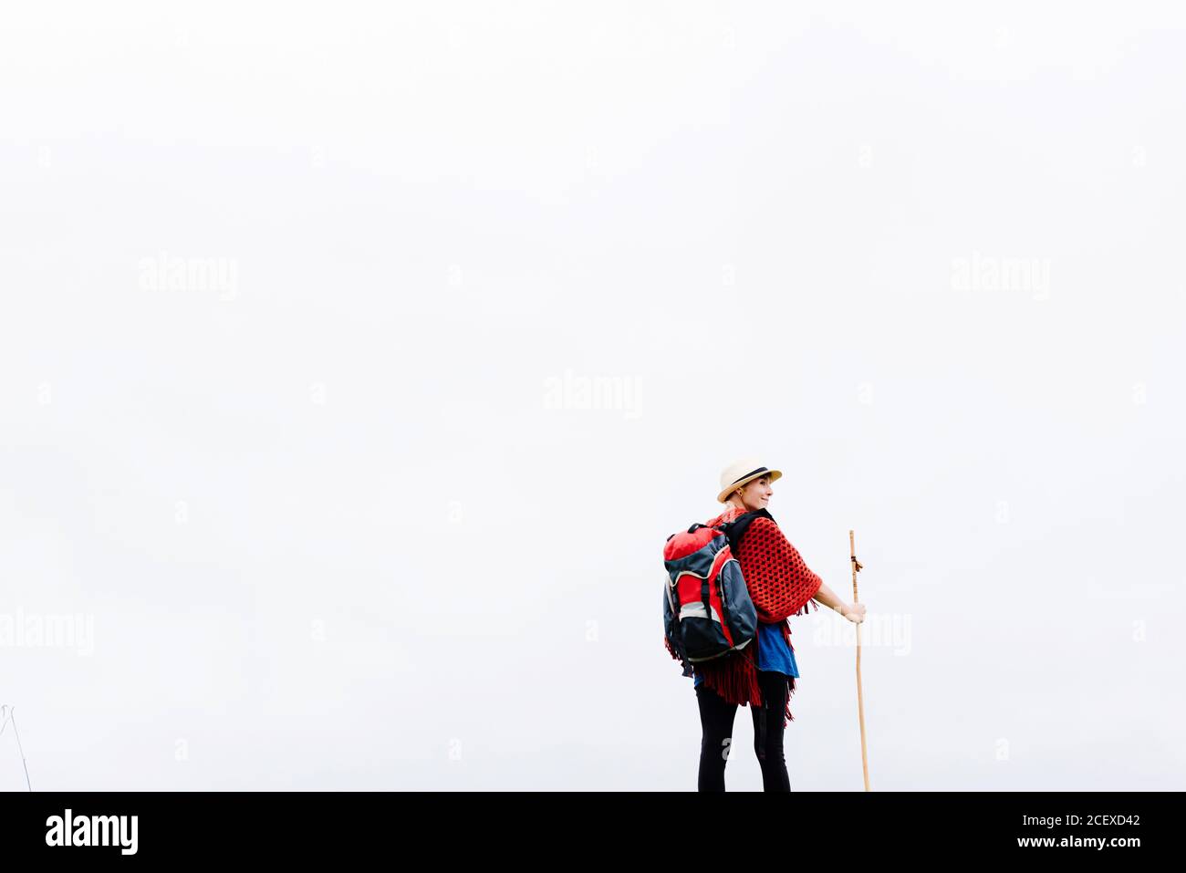 Vue arrière d'une randonneur femelle avec un bâton de randonnée debout contre Ciel gris nuageux et liberté pendant le pèlerinage à travers l'Espagne Banque D'Images