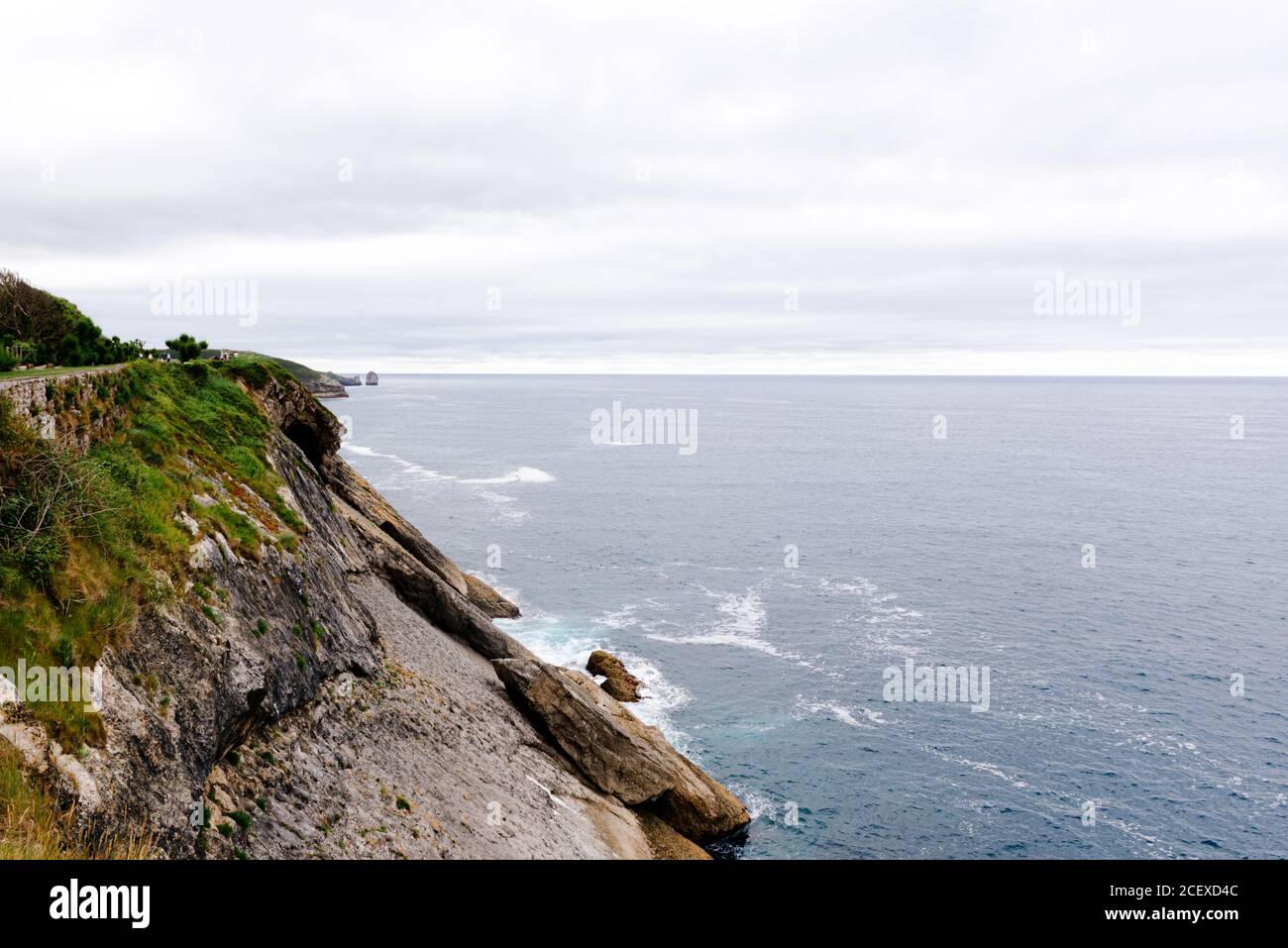 Vagues de mer mousseuse éclaboussant sur la côte rocheuse en été nuageux Journée dans les Asturies en Espagne Banque D'Images