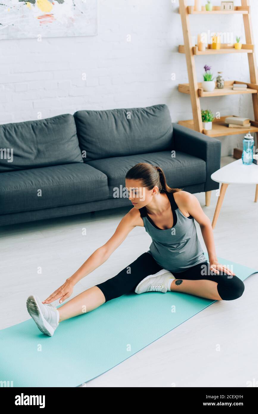 Femme enceinte dans des vêtements de sport s'étendant sur le sol à la  maison Photo Stock - Alamy