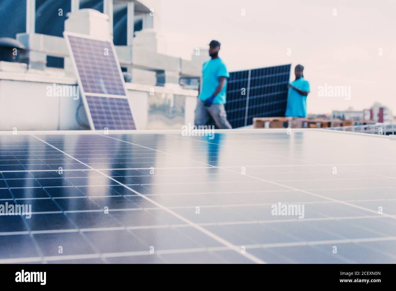 Panneaux solaires contemporains installés en rangées dans la zone industrielle de usine sur fond de travailleurs ethniques méconnaissables Banque D'Images