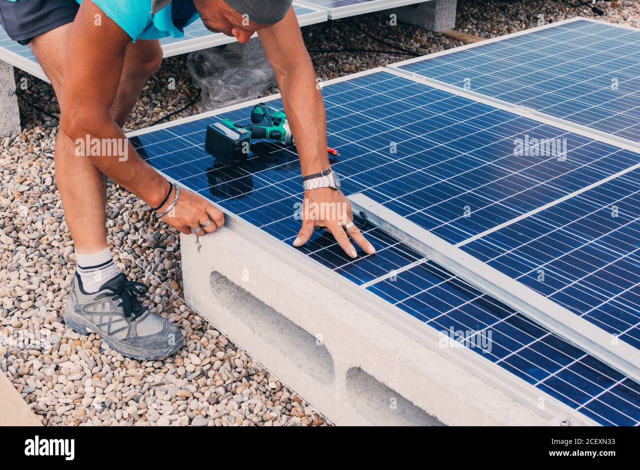 ingénieur anonyme utilisant un tournevis électrique et l'installation solaire contemporaine batterie en usine Banque D'Images