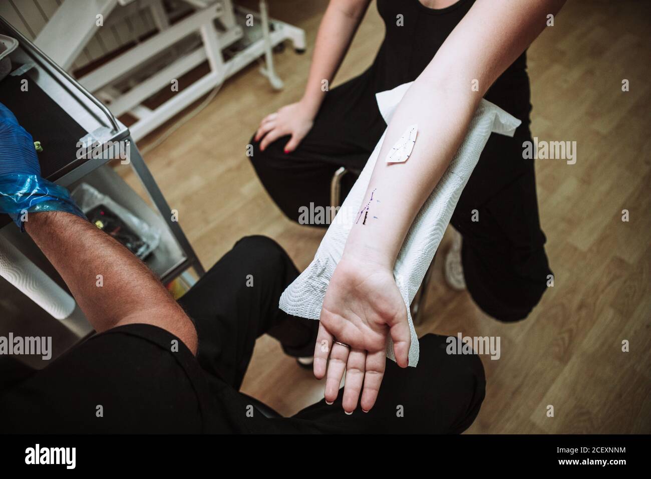 Du dessus de la récolte anonyme homme tatoueur se préparant à la fabrication tatouage au poignet de la cliente dans un salon moderne Banque D'Images