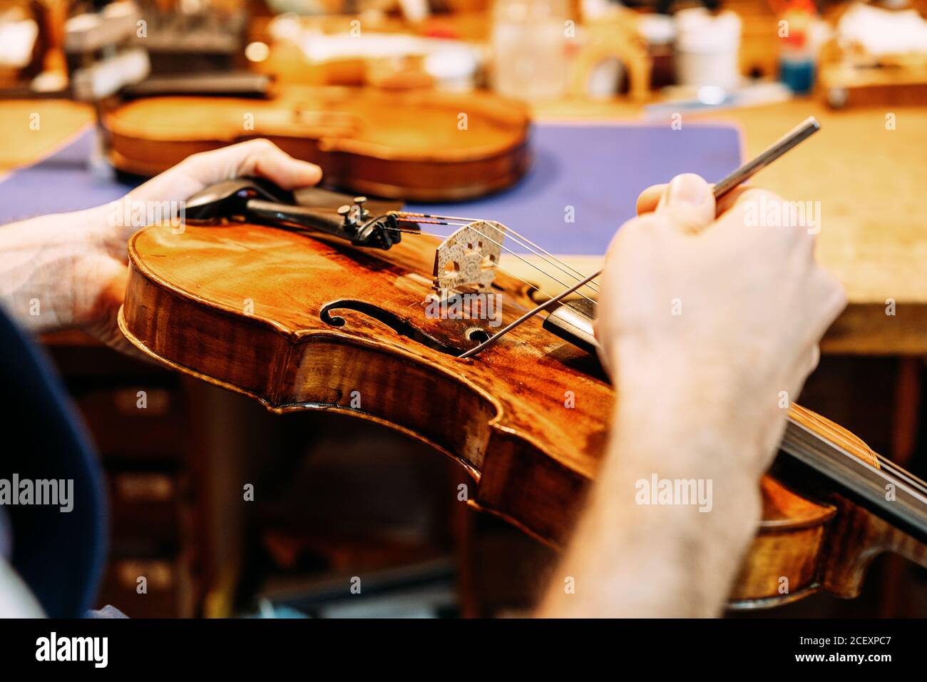 Crop artisan luthier avec outil de réparation de métal pointue à F trou de vieux violon pendant les travaux de restauration en atelier Banque D'Images