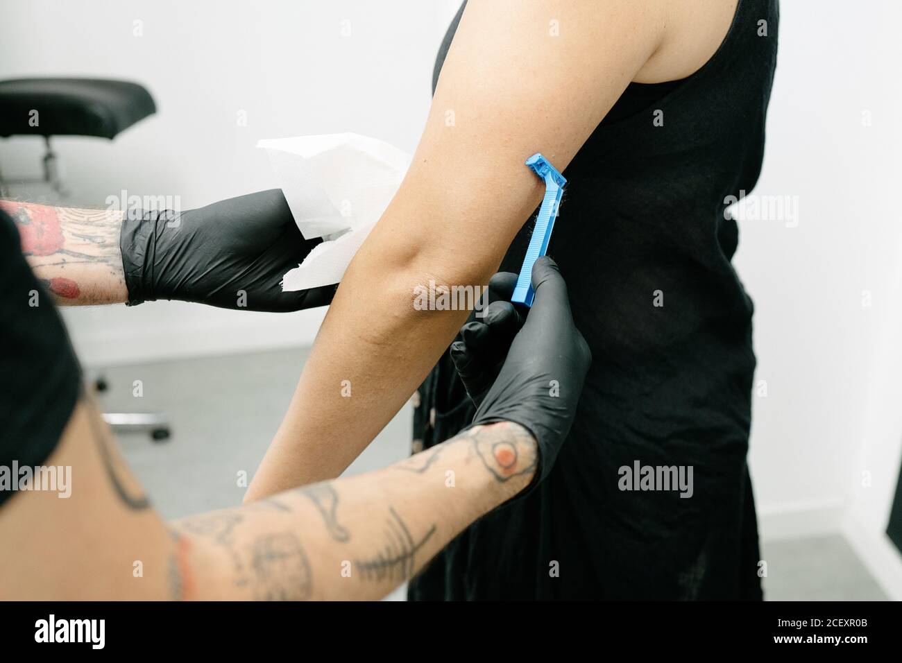bras de rasage de tatouage masculin non reconnaissable de la cliente de  femme avec tranchant rasoir tout en se préparant au tatouage dans un salon  moderne Photo Stock - Alamy