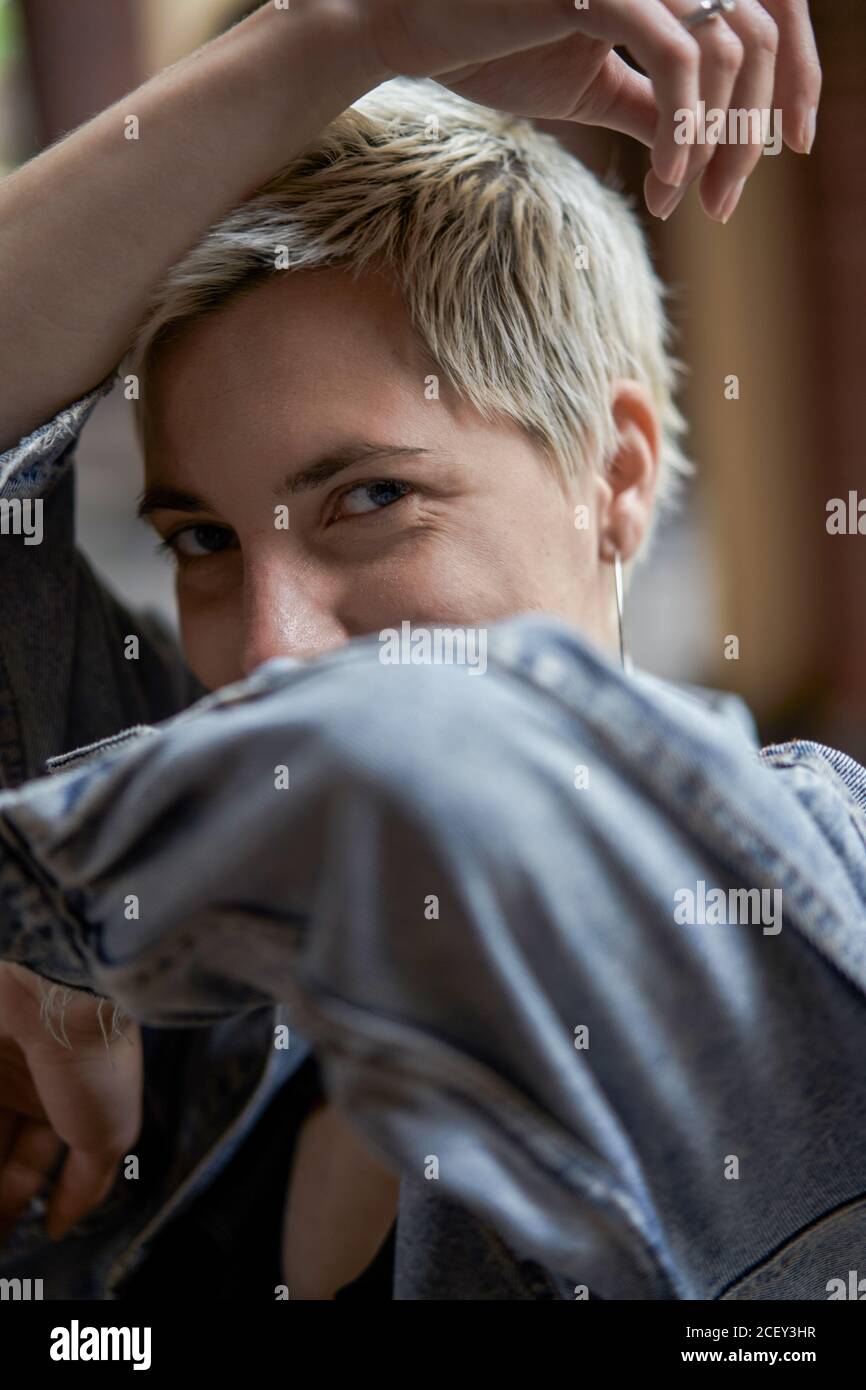 Vue latérale d'une femme heureuse avec couvre-cheveux court debout faites face à une veste en denim dans la rue tout en regardant appareil photo Banque D'Images