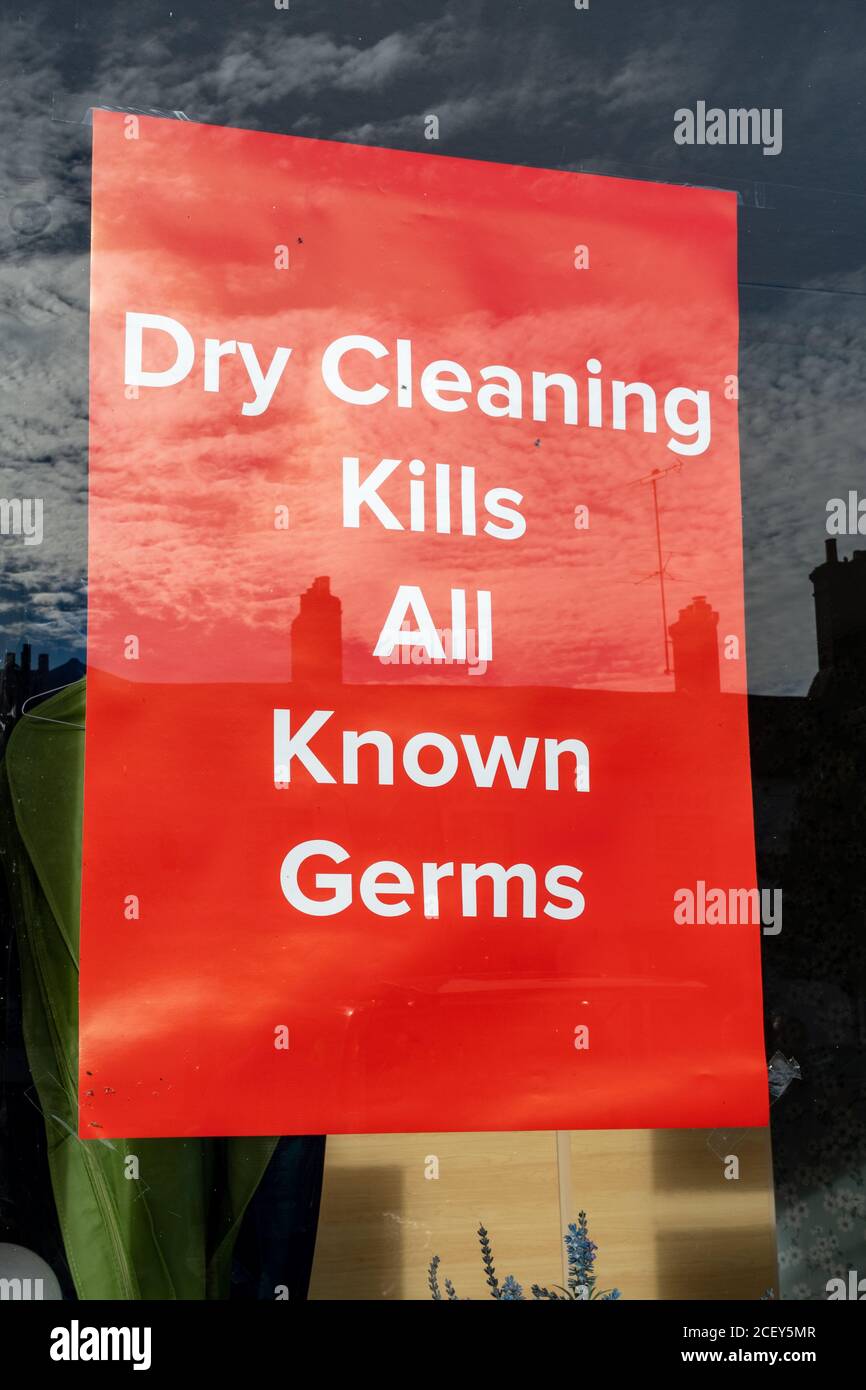 Avis dans la fenêtre de l'atelier de nettoyage à sec indiquant que le nettoyage à sec tue tous les germes connus, en référence à la pandémie du coronavirus covid-19 Banque D'Images