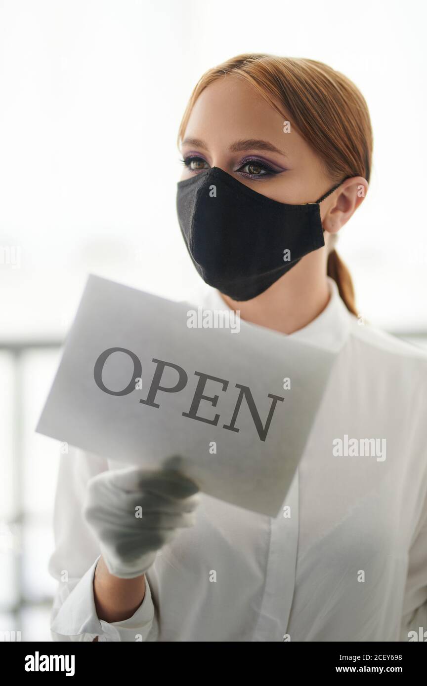 Rouvrir les activités après une pandémie de virus. Une jeune femme tourne le panneau de porte Banque D'Images