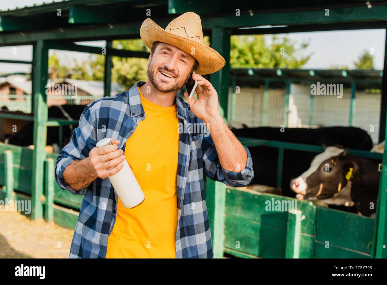 fermier en chemise à carreaux et chapeau de paille contenant une bouteille  de du lait frais tout en parlant sur votre smartphone Photo Stock - Alamy