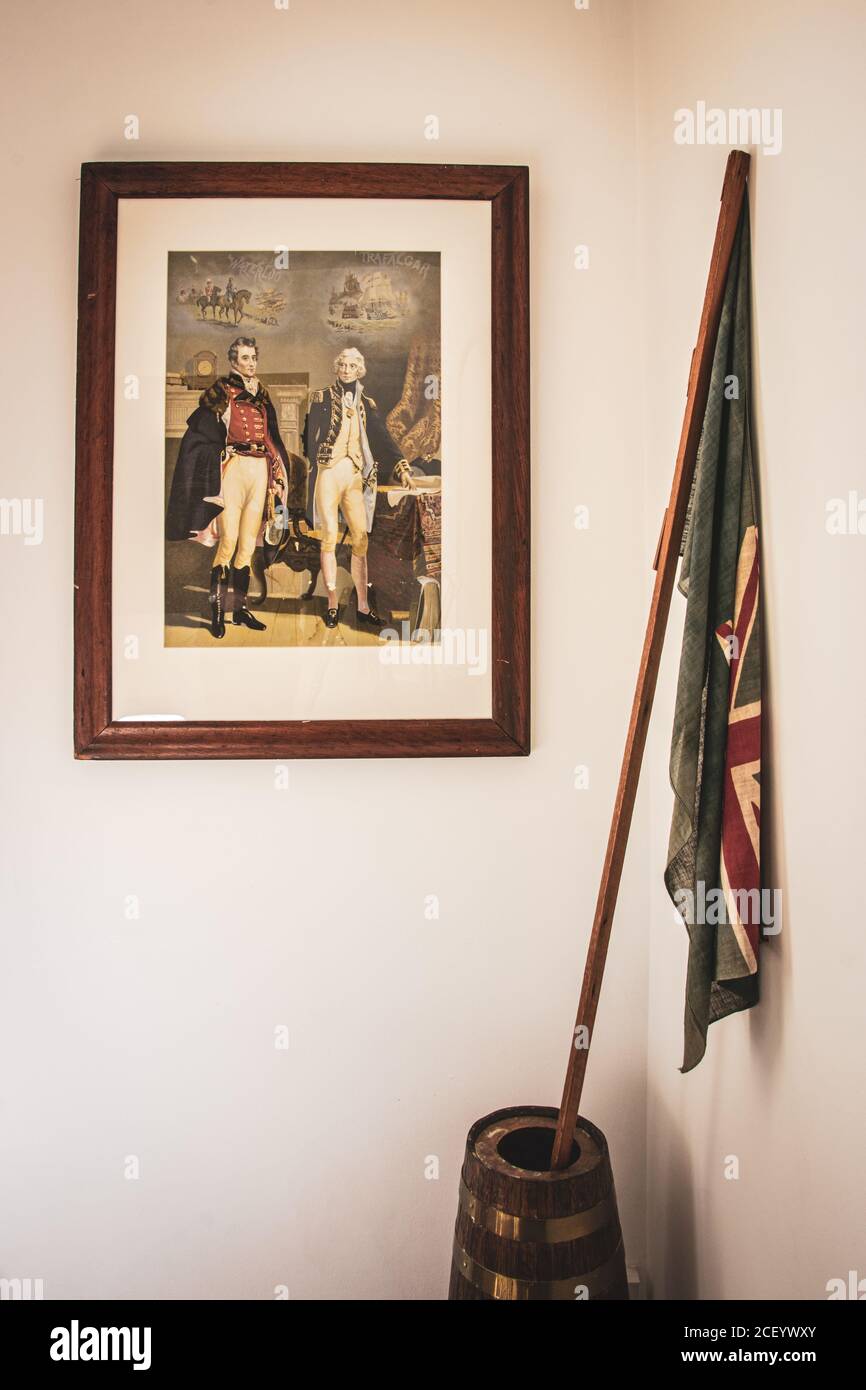 Œuvres d'art sur le thème de la marine sur un mur d'une maison avec Un vieux drapeau naval Ensign à ses côtés Banque D'Images
