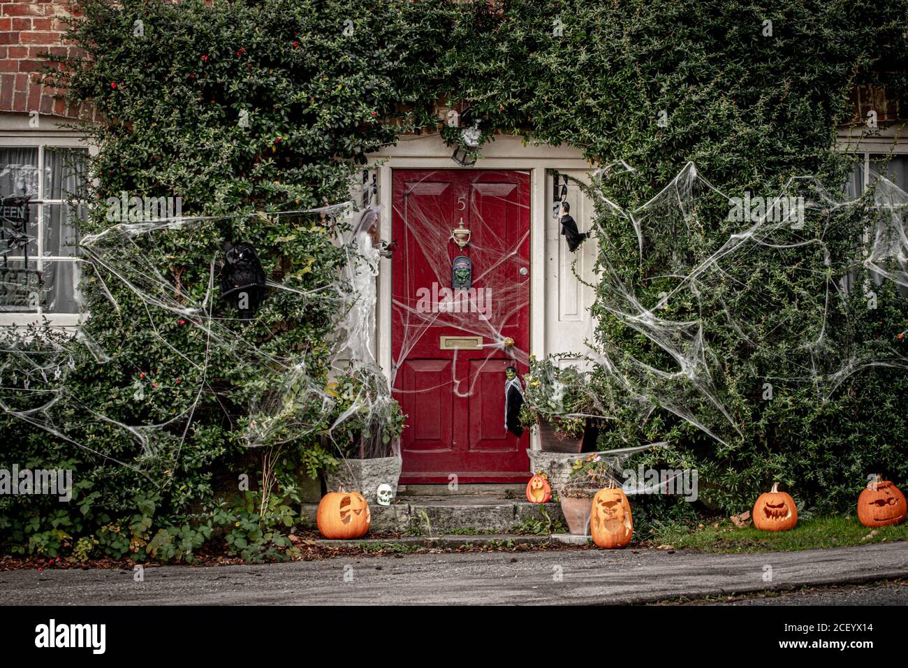 L'extérieur d'un cottage de campagne anglaise décoré pour Halloween avec des citrouilles à la porte et des toiles d'araignées ou des toiles d'araignée en descendant Banque D'Images