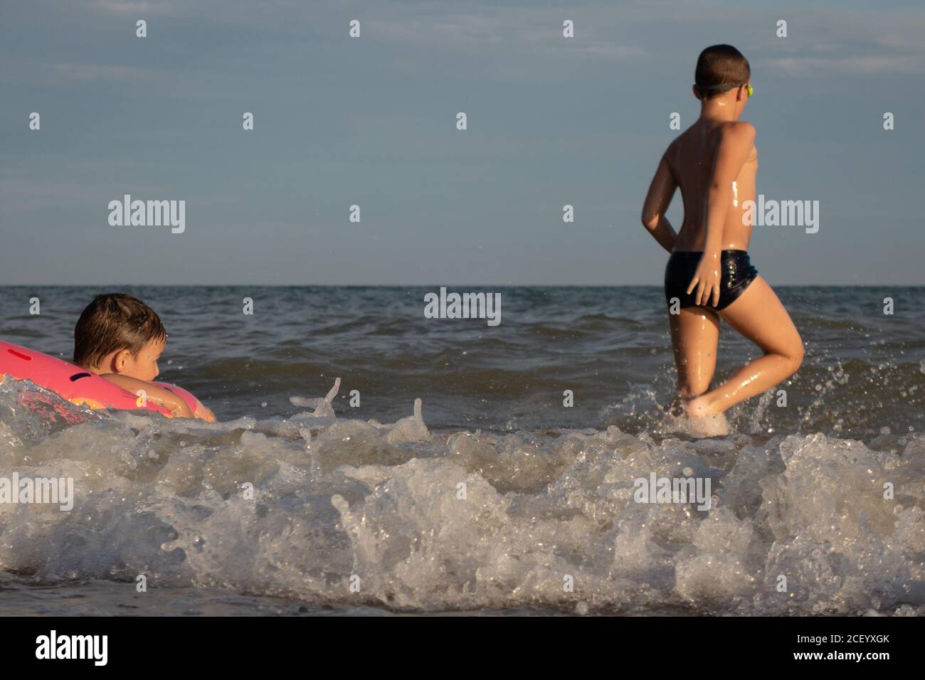 Deux frères de 5 et 10 ans nagent et s'amusent dans la mer par une journée ensoleillée. Banque D'Images