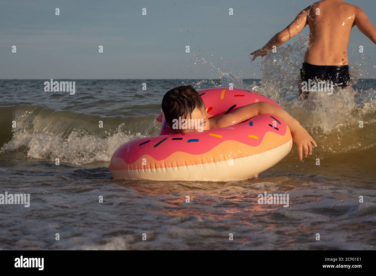 Deux frères de 5 et 10 ans nagent et s'amusent dans la mer par une journée ensoleillée. Banque D'Images