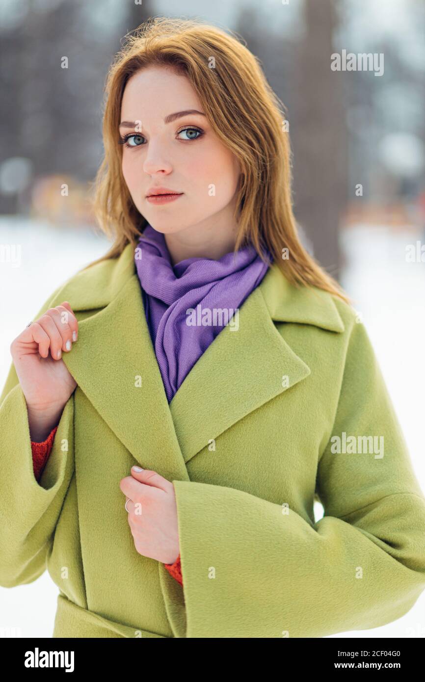 portrait d'une femme à poil court, vêtue d'un long manteau vert, dans une  rue enneigée en hiver. magnifique modèle de jeune femme en mode luxuriant  Photo Stock - Alamy