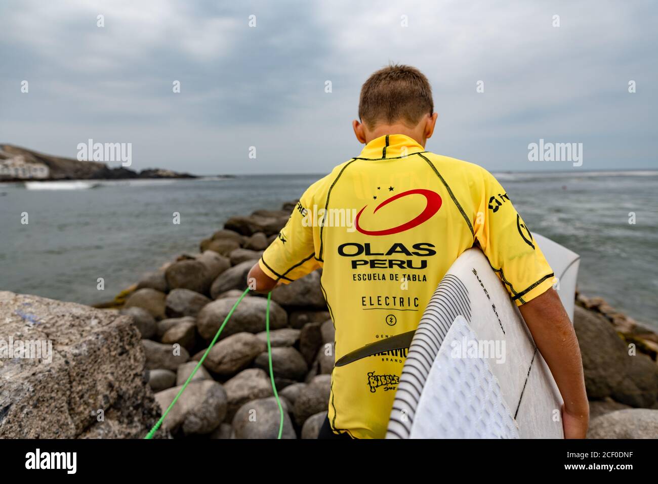 Vue arrière d'un jeune surfeur portant sa planche de surf lors de la compétition 'SEMILLERO OLAS PERUs' à San Bartolo, Pérou. Mars 2020 Banque D'Images