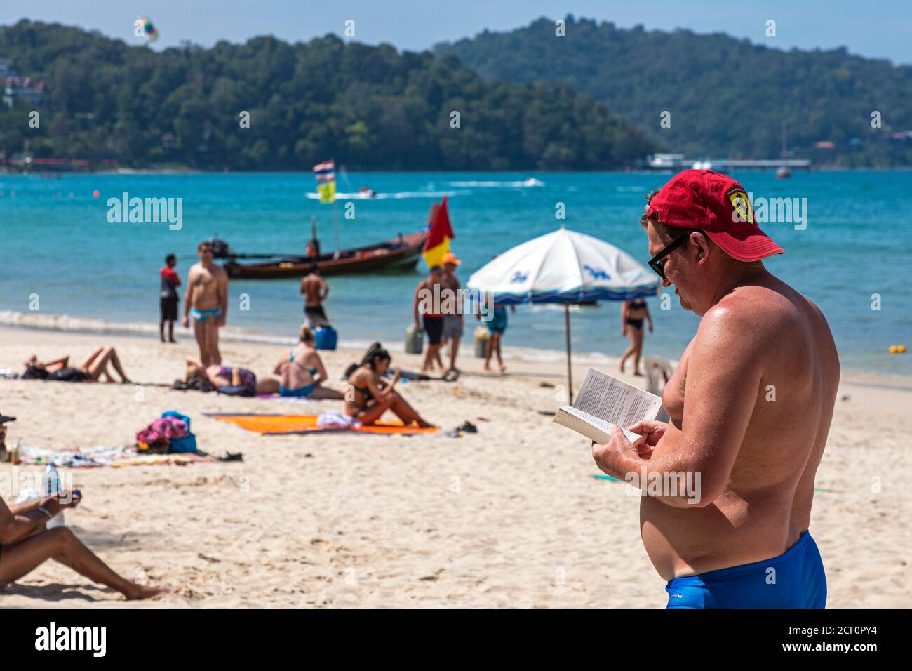 Touristes russes, lecture et bains de soleil se tenant sur la plage de Patong, Phuket, Thaïlande Banque D'Images
