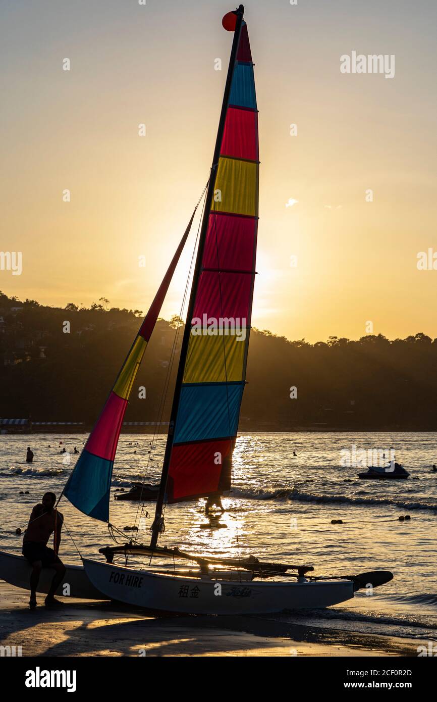 Location de bateau à voile sur la plage de Patong au coucher du soleil, Phuket, Thaïlande Banque D'Images