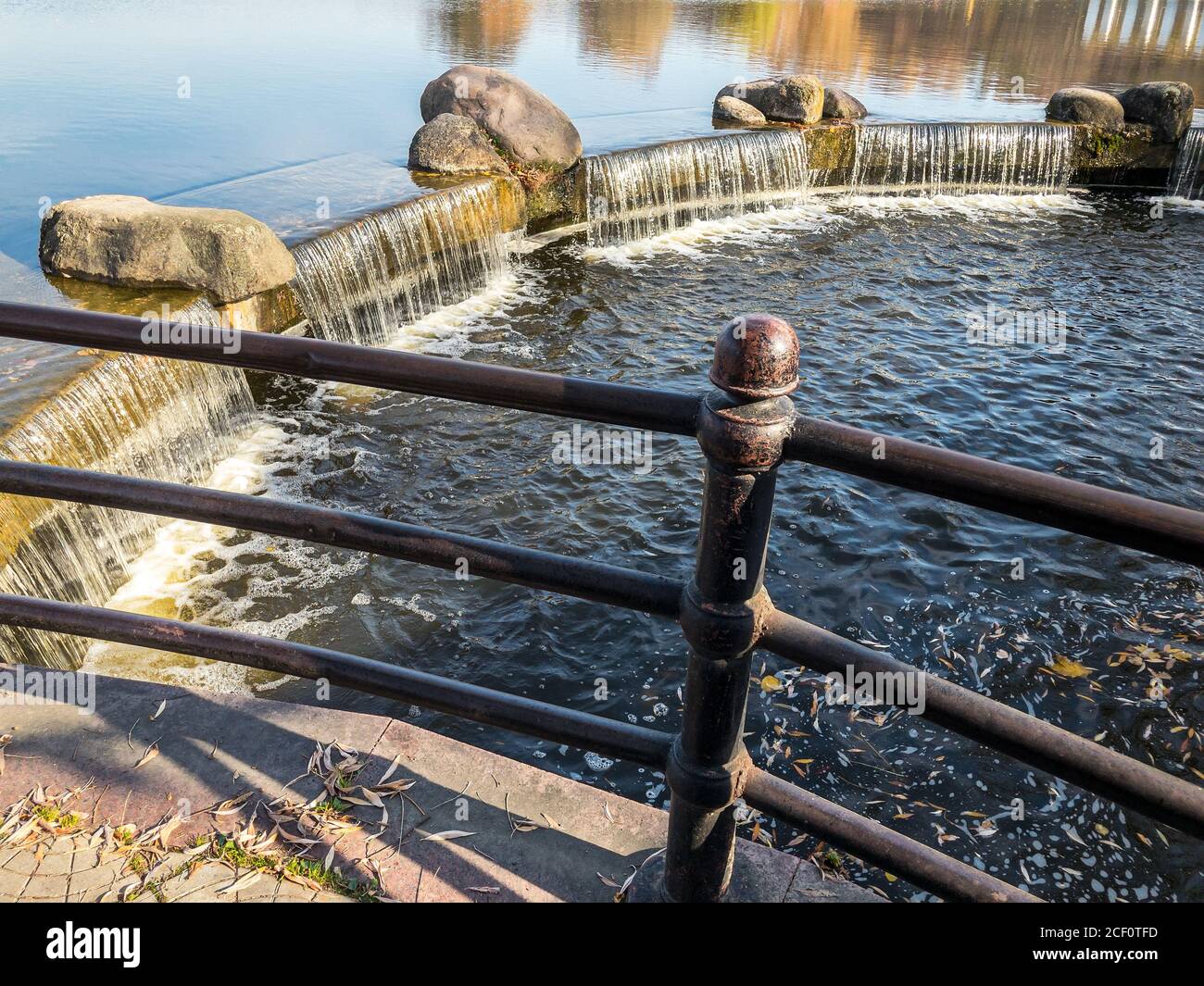 petite cascade artificielle avec pierres sur le lac dans le parc public. jour d'automne ensoleillé Banque D'Images