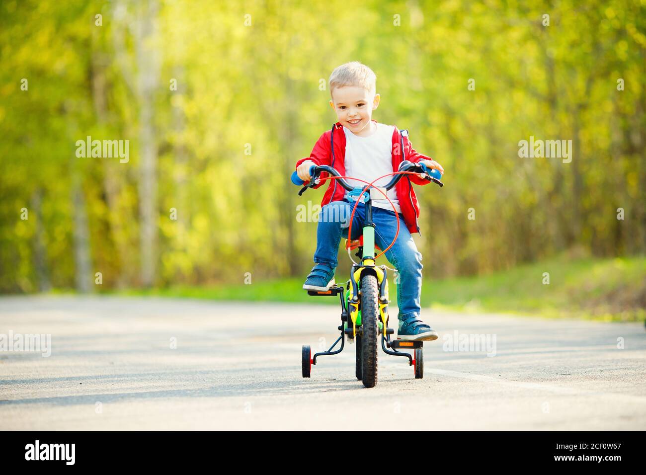 Happy boy fait du vélo et sourit dans le parc d'été. Concept d'entraînement Banque D'Images