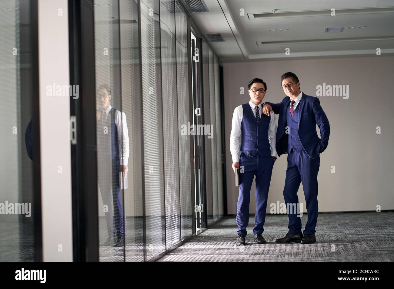 portrait de deux dirigeants d'entreprises asiatiques debout dans un bureau à l'appareil photo Banque D'Images
