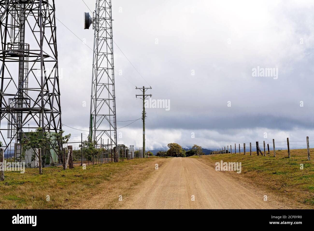 Les tours de communication modernes de technologie à côté d'une route de terre dans un cadre rural Banque D'Images