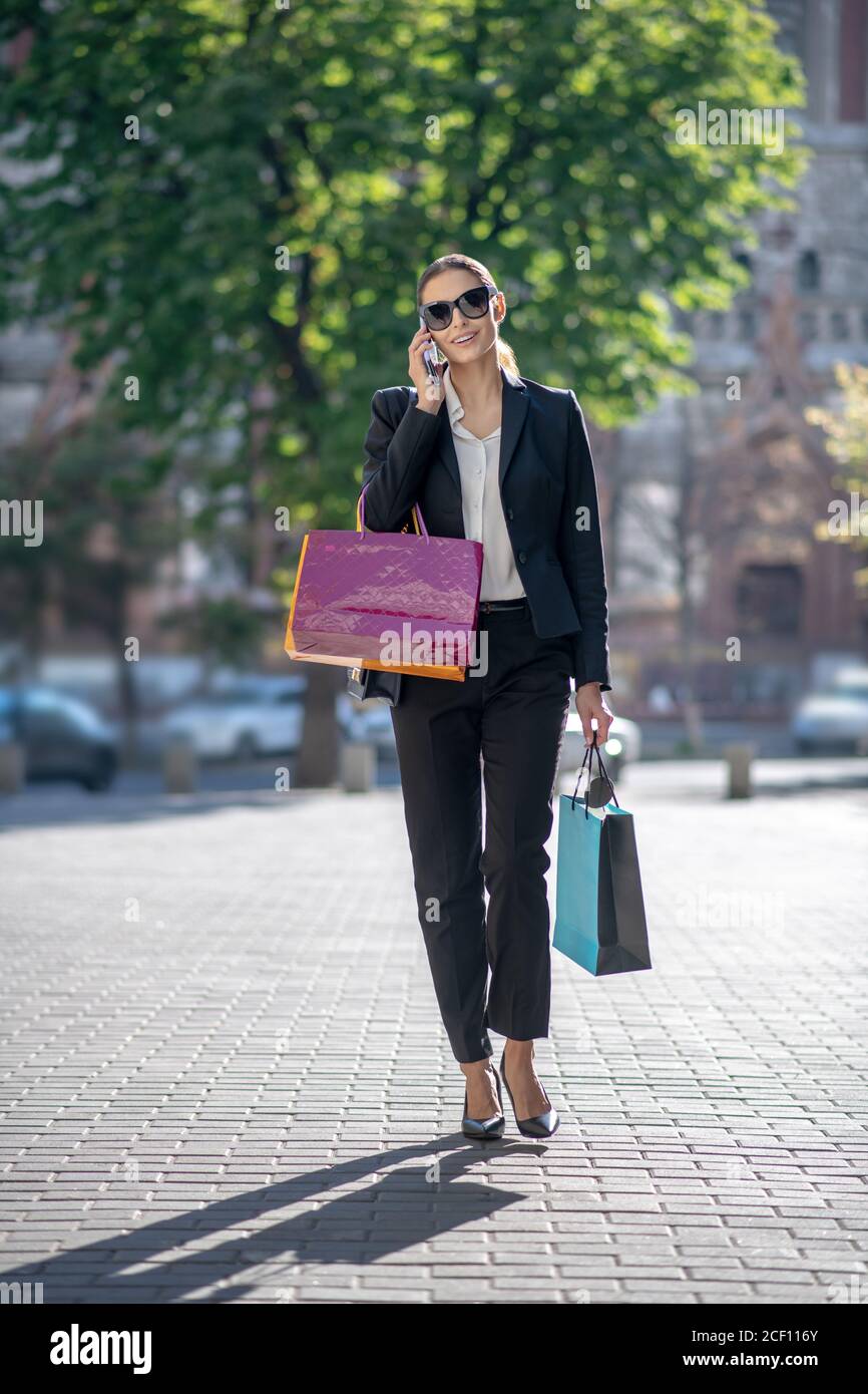 Femme élégante aux cheveux sombres avec des sacs de shopping dans la rue Banque D'Images