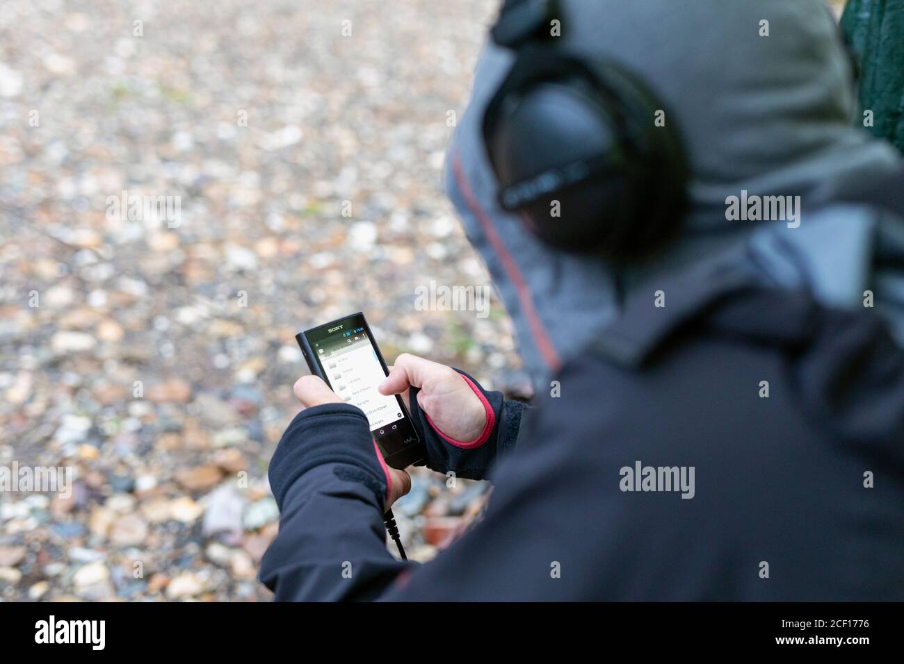 un homme assis avec son dos utilise un smartphone, regarde la liste de lecture sur le téléphone et écoute de la musique. Russie, Bashkortostan, juillet 2019. Banque D'Images