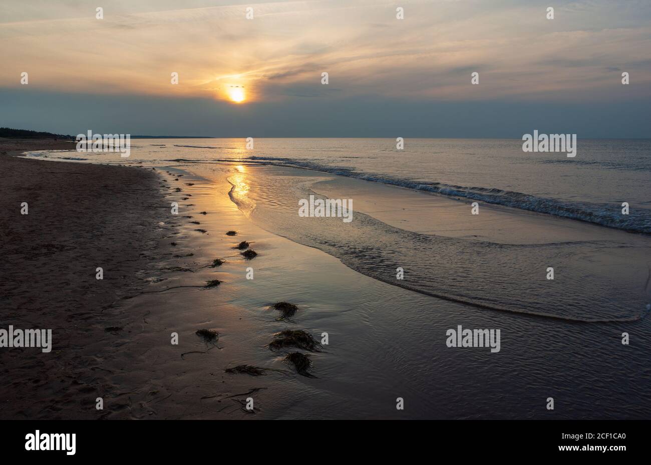 Scintillent le soleil sur les vagues. Disque solaire transitoire éblouit au-dessus d'un horizon sombre. Cavendish Beach, parc national de l'Île-du-Prince-Édouard, Canada Banque D'Images