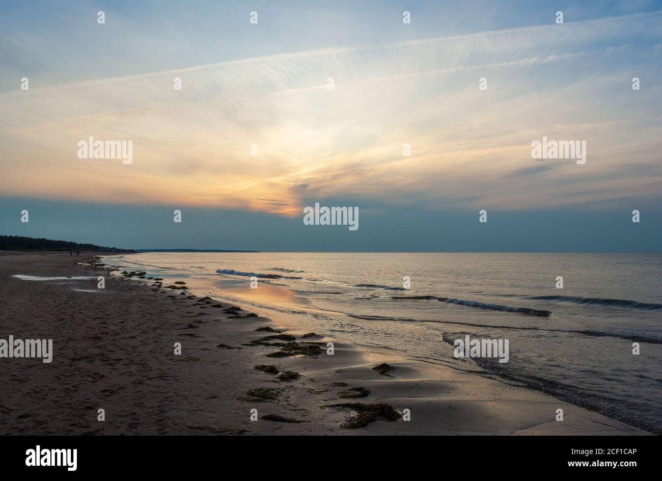 Plage déserte au crépuscule. Le coucher du soleil se reflète sur les eaux calmes de l'océan. Cavendish Beach, parc national de l'Île-du-Prince-Édouard, Canada Banque D'Images