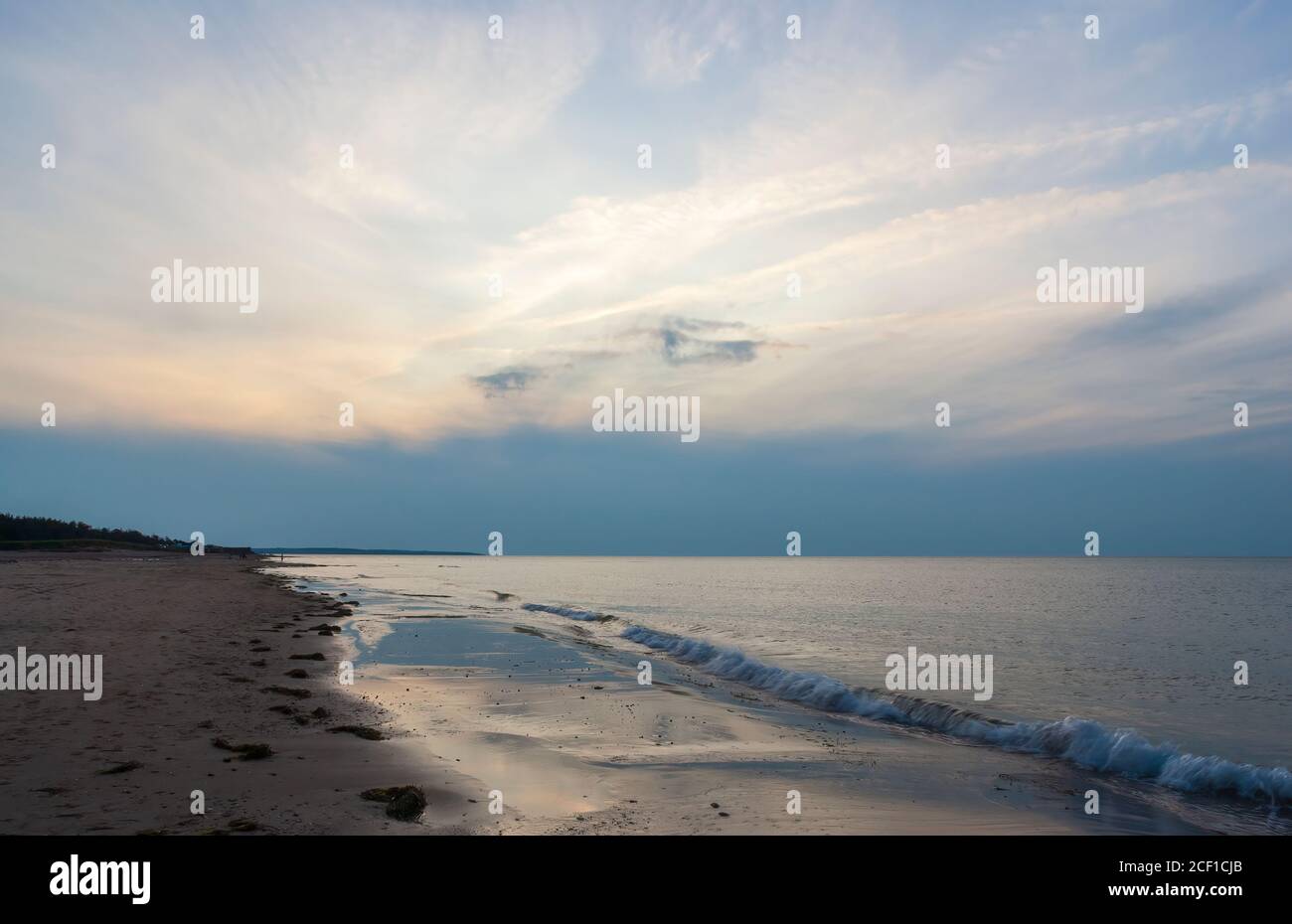 Plage déserte au crépuscule. Ciel nuageux dans des tons bleus reflétés sur les eaux calmes de l'océan. Cavendish Beach, parc national de l'Île-du-Prince-Édouard, Canada Banque D'Images