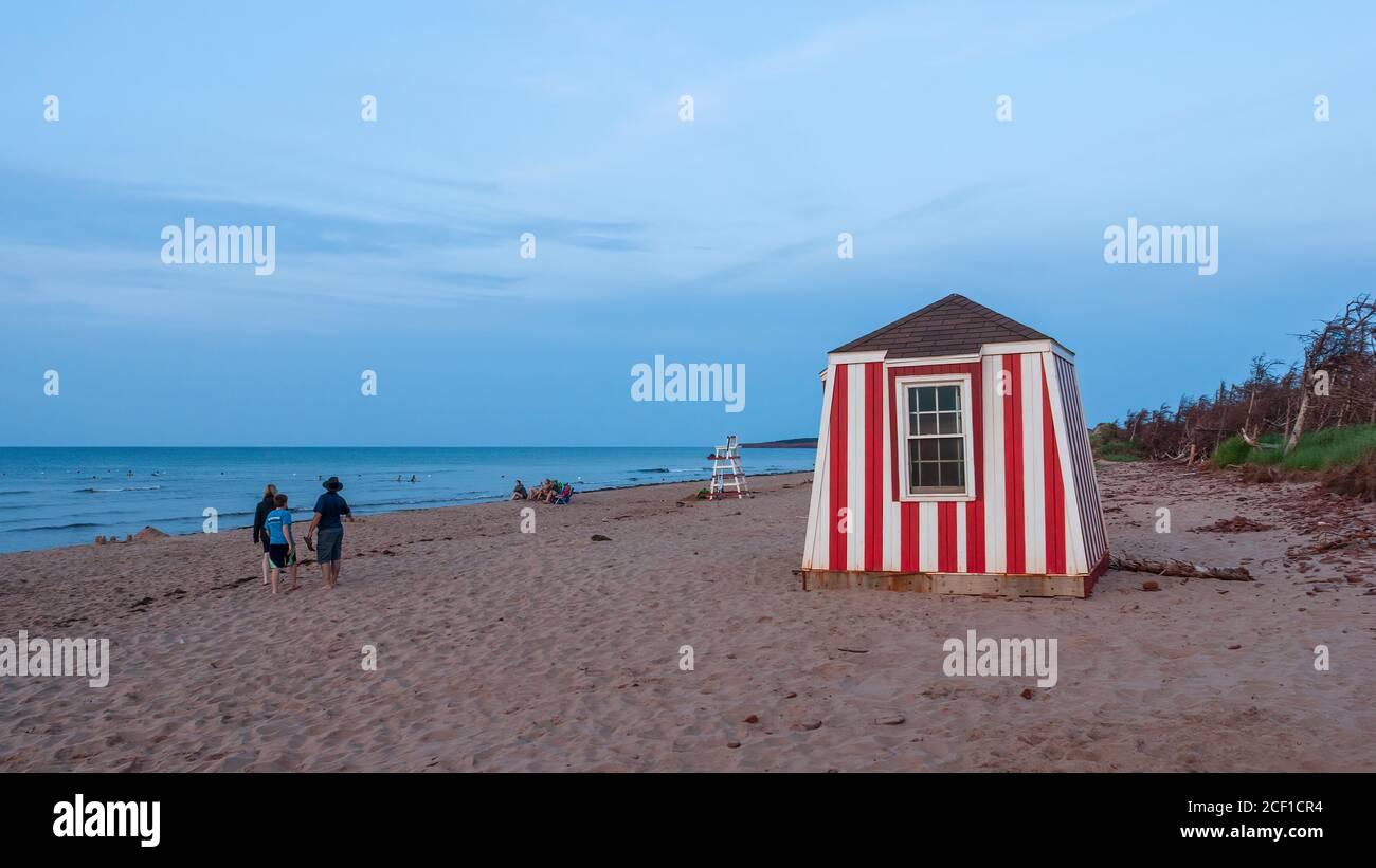 Les gens se détendent sur la plage au coucher du soleil. Enfants jouant dans les eaux peu profondes. Station de secouriste et chaise d'observation. Cavendish Beach, Î.-P.-É., Canada. Banque D'Images