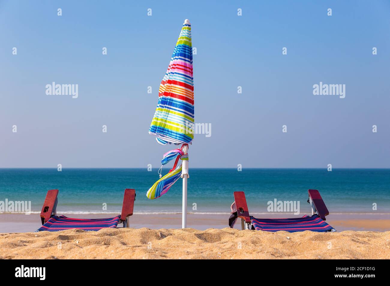 Parasol coloré avec chaises sur la plage avec bleu océan Banque D'Images