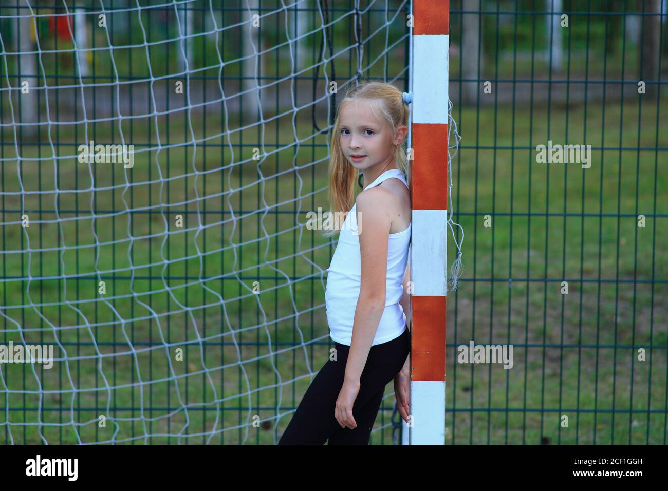 Une fille posant près d'un but de football sur un terrain de sport. Banque D'Images
