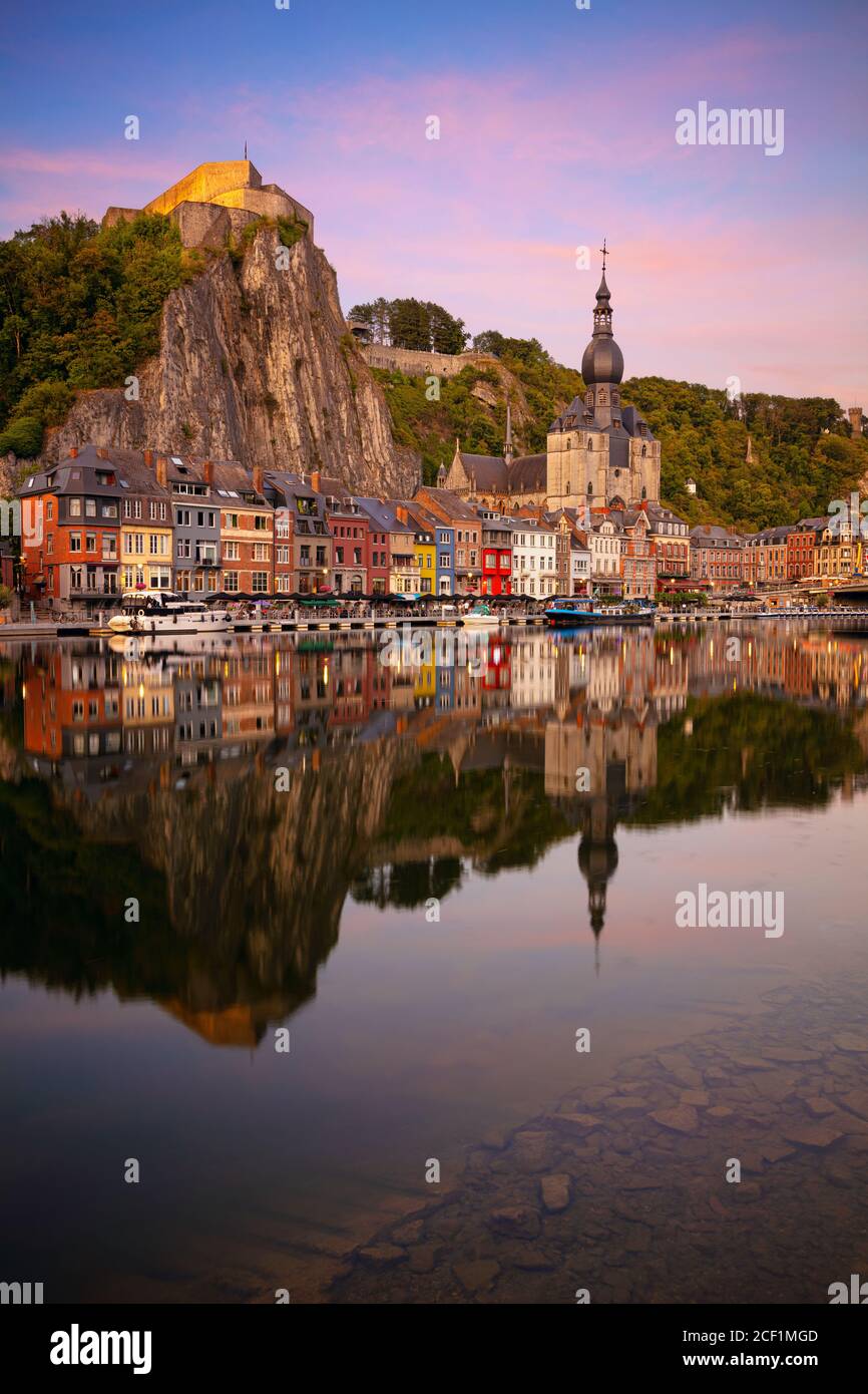 Dinant, Belgique. Image de paysage urbain de la belle ville historique de Dinant avec le reflet de la ville dans la Meuse au coucher du soleil d'été. Banque D'Images