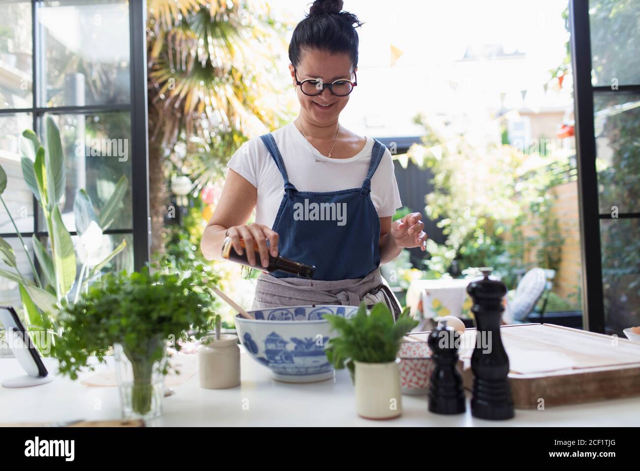 Femme souriante cuisant au vinaigre balsamique dans la cuisine Banque D'Images