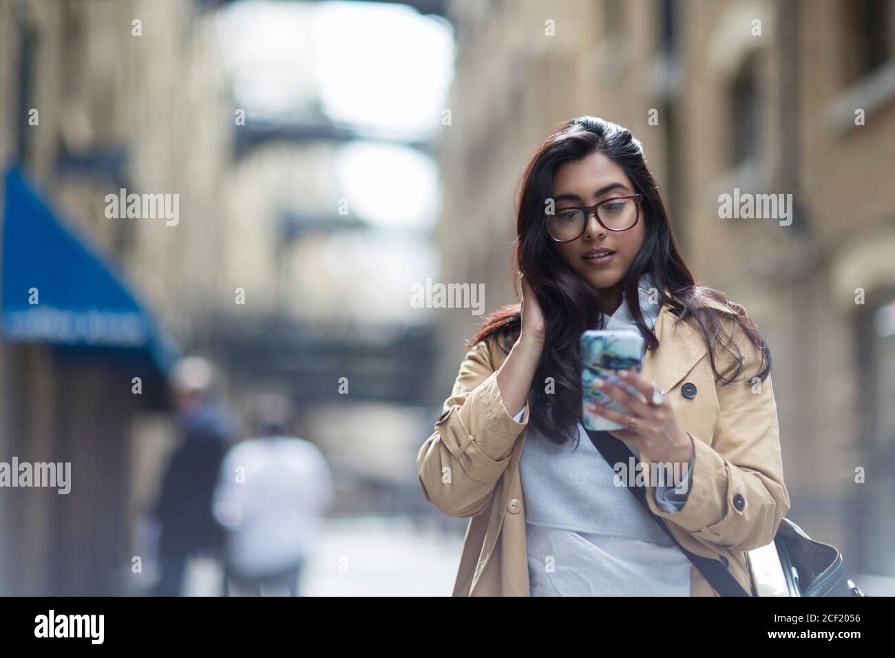 Businesswoman using smart phone on sidewalk Banque D'Images