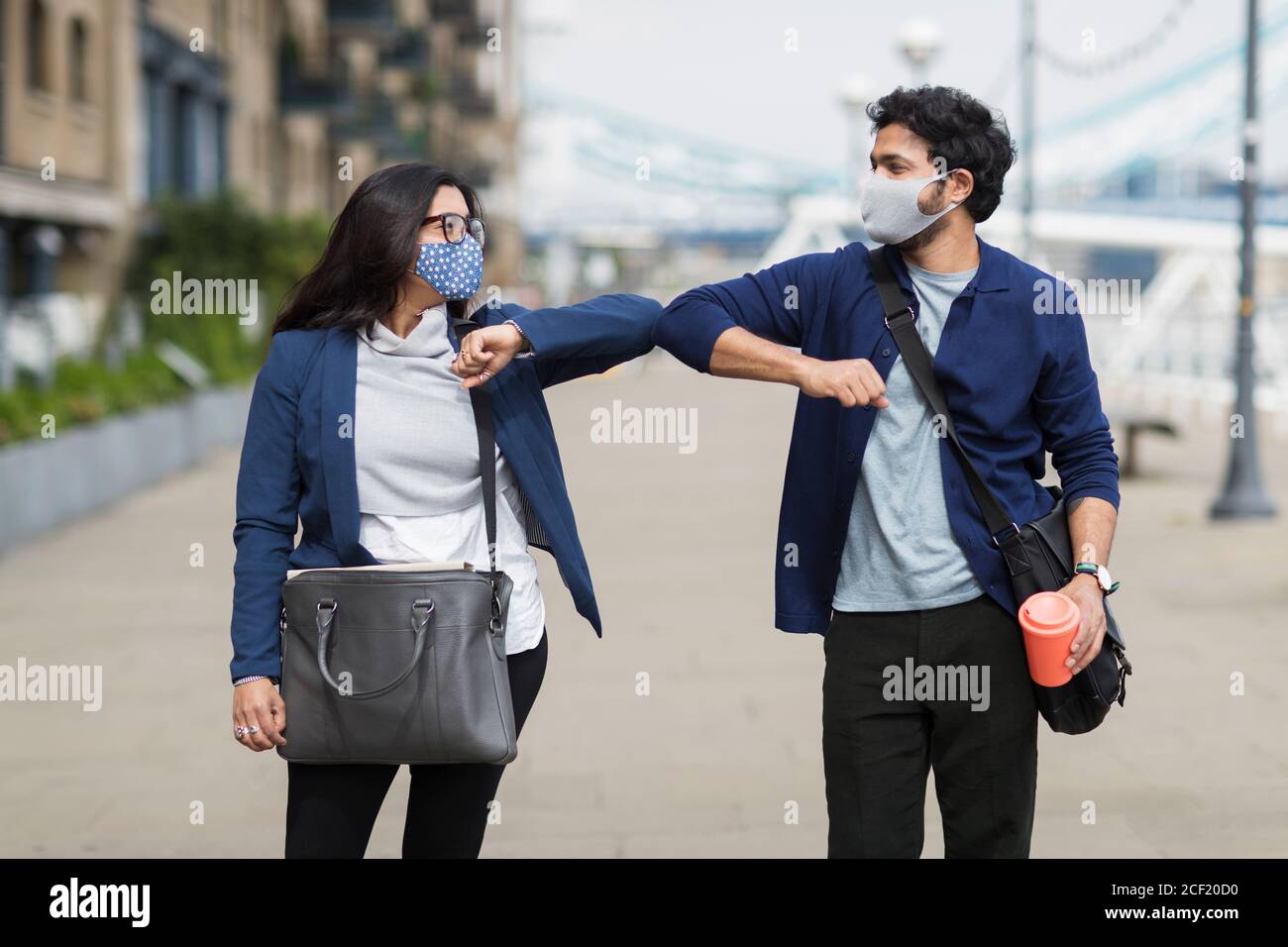 Les gens d'affaires dans les masques de visage touchant les coudes dans la rue de la ville Banque D'Images