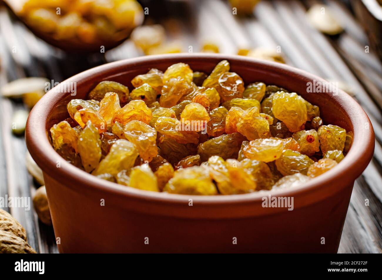 Raisins blancs dans un bol en argile sur une table de cuisine en bois fond de nourriture. Banque D'Images