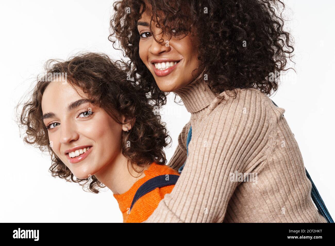 Image de filles multiraciales heureux amis en denim combinaisons isolées sur fond de mur blanc ayant le plaisir. Banque D'Images
