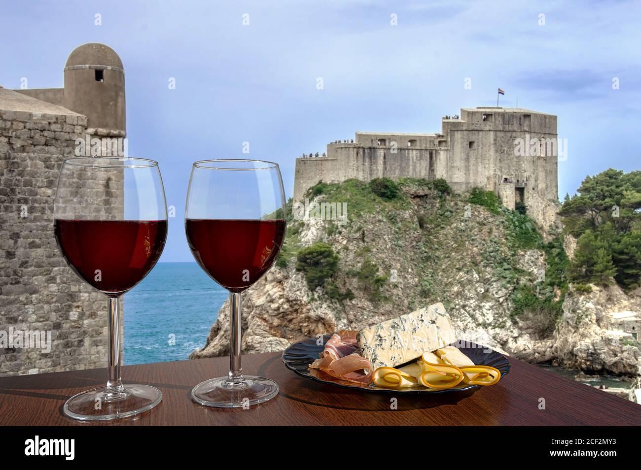 Deux verres de vin avec vue sur la forteresse de Lovrijenac depuis les remparts de Dubrovnik, Dubrovnik, Croatie. Verre de vin rouge avec différents en-cas - assiette wi Banque D'Images