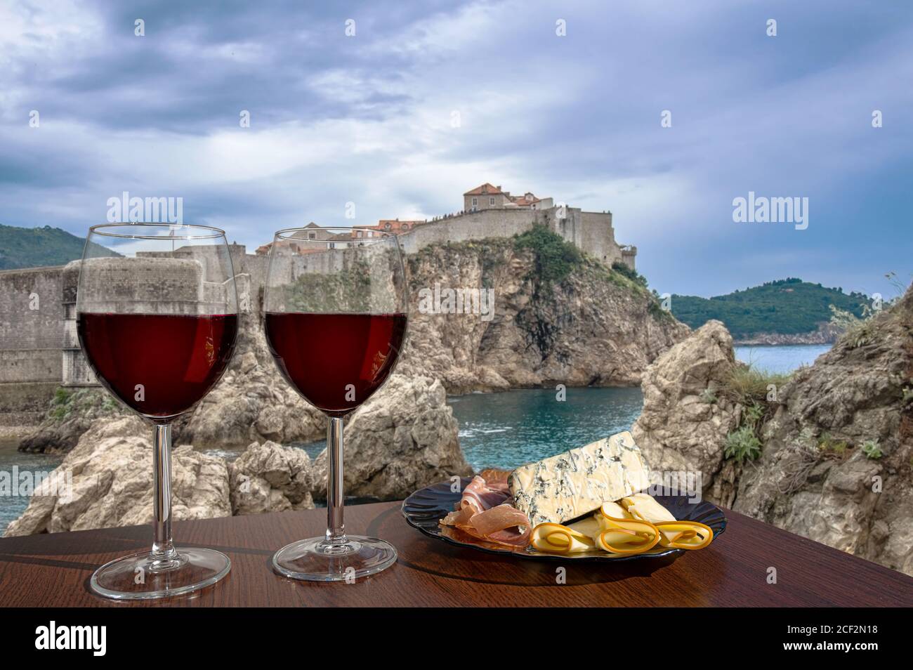 Deux verres de vin avec assortiment de fromage et de viande sur la vue des murs de la forteresse, côte rocheuse et mer bleue à Dubrovnik, Croatie. Vue imprenable sur du Banque D'Images