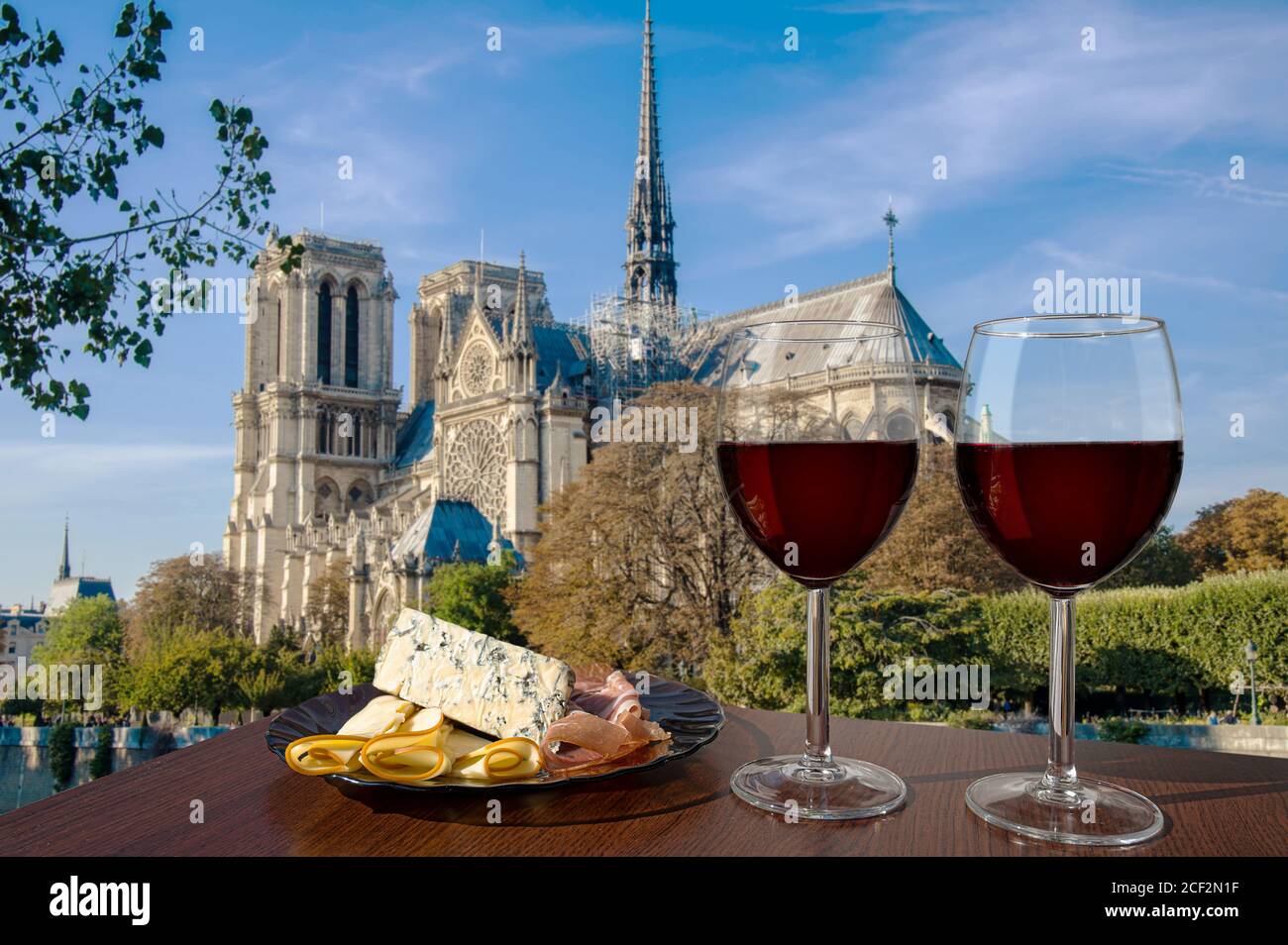 Deux verres de vin rouge avec assortiment de fromages et de viandes contre notre Dame de Paris ou la cathédrale notre-Dame de Paris, France. Célébration romantique. Banque D'Images