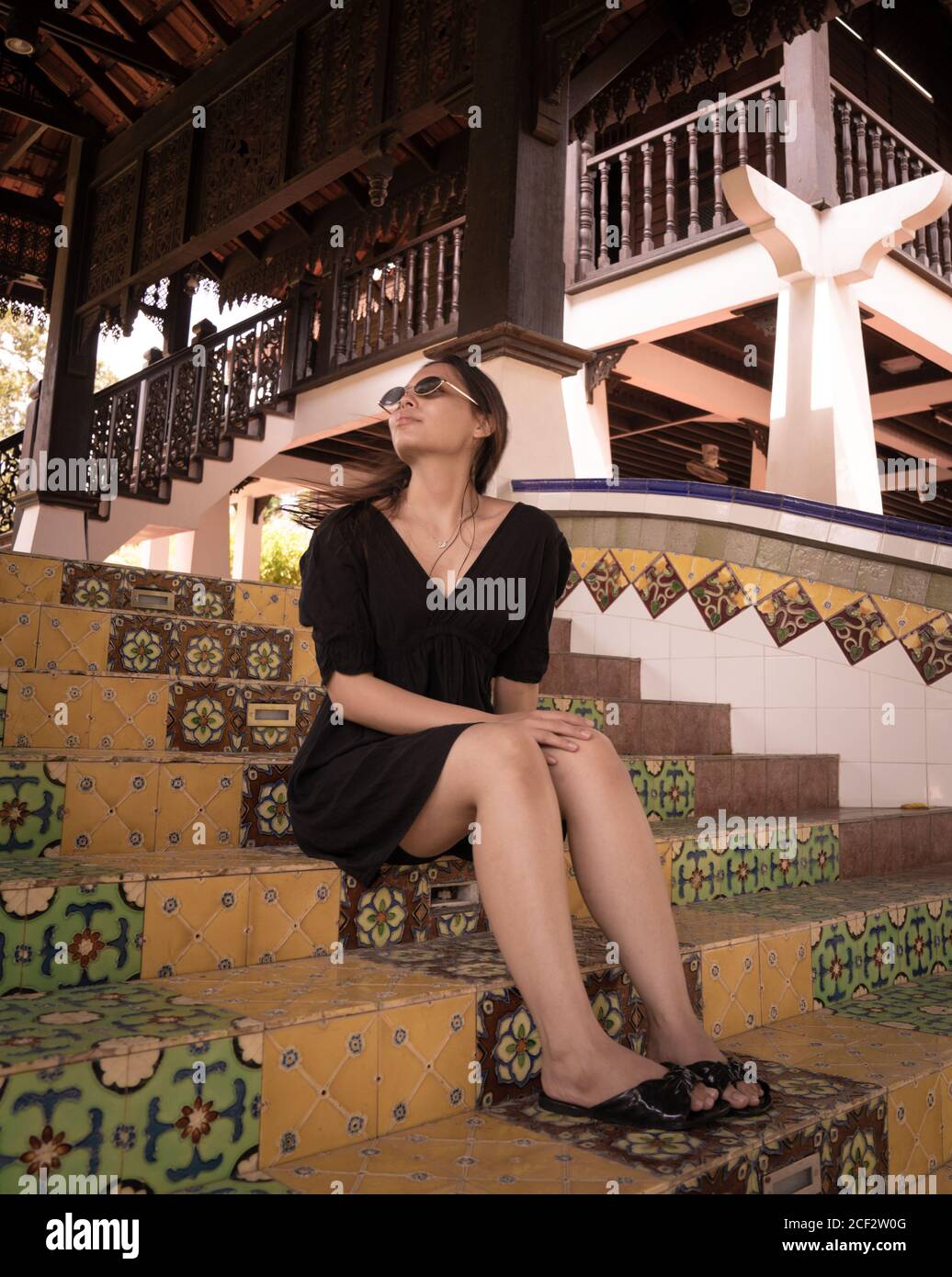 Brunette jeune fille assise sur un escalier avec des carreaux portugais en été Banque D'Images