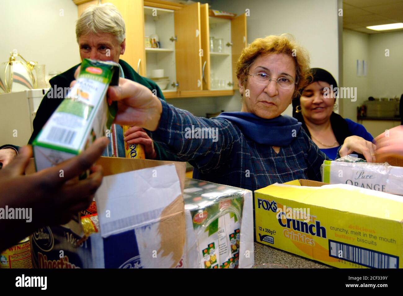 Les volontaires donnent de la nourriture gratuite après sa date limite de vente pour les réfugiés et les demandeurs d'asile dans une cuisine à soupe dans un hall d'église ; Bradford Yorkshire UK Banque D'Images
