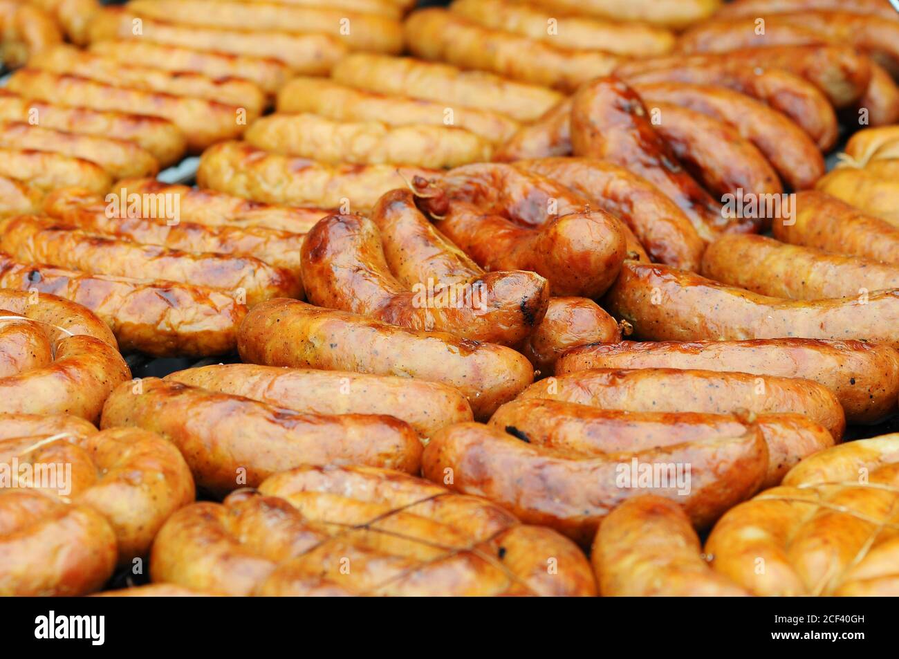 Saucisses fraîches et des hot-dogs sur le gril en plein air sur un barbecue à gaz. Banque D'Images