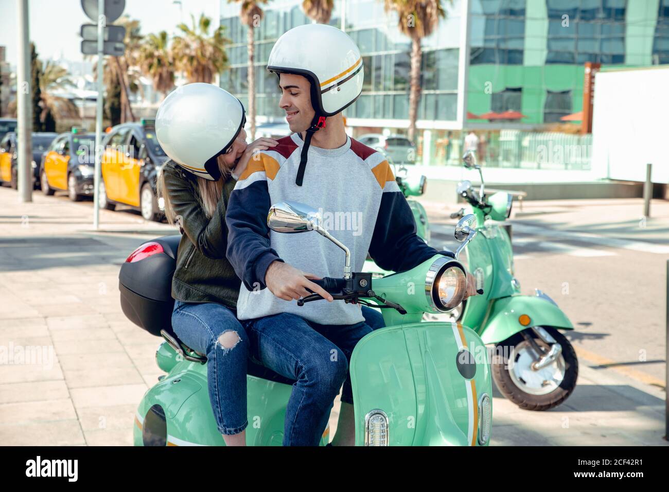 Jeune couple en casques de moto assis ensemble sur le vélo vert et parler  sur la rue Photo Stock - Alamy