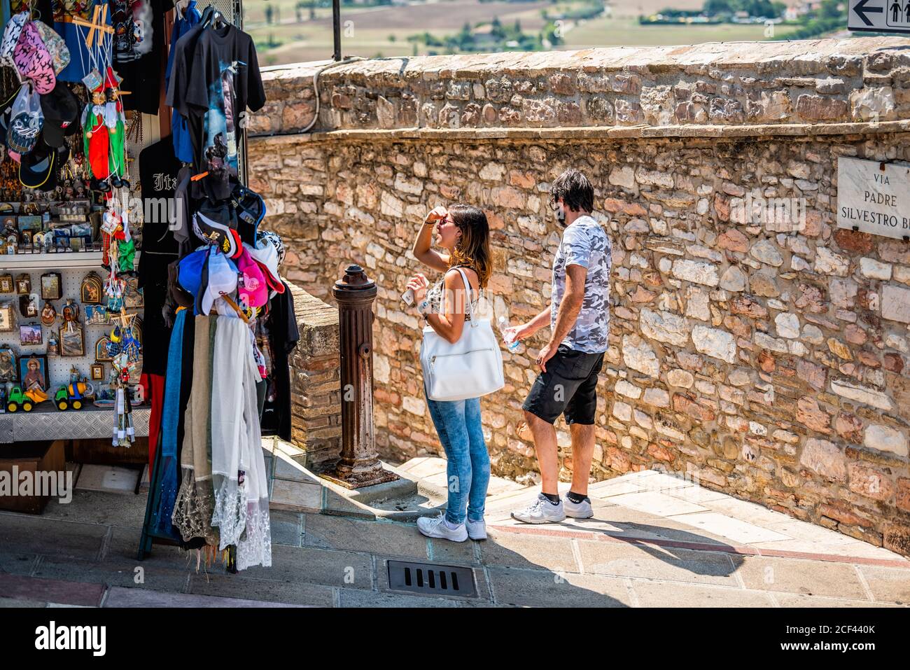 Assisi, Italie - 29 août 2018 : village de la ville d'Ombrie avec une femme dans un petit magasin vendeur de kiosque vendant des cadeaux souvenirs exposés Banque D'Images