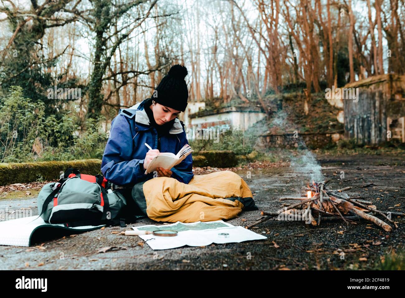 Une jeune femme routard prend des notes au feu de camp Banque D'Images