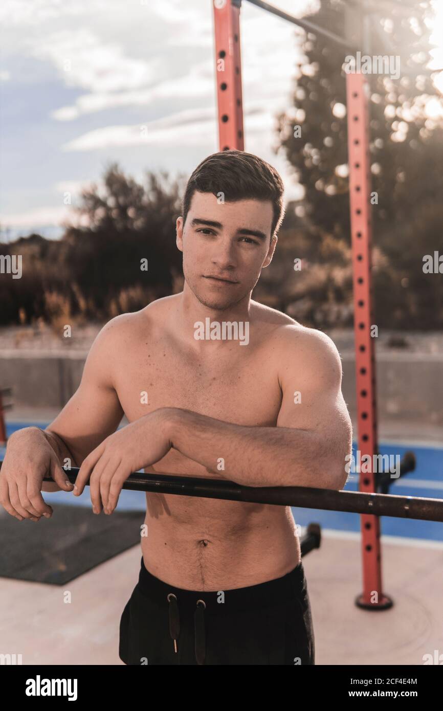 Jeune homme sans chirboul s'inclinant au bar et regardant l'appareil photo en vous pratiquant sur un terrain de sport par beau temps rue de la ville Banque D'Images