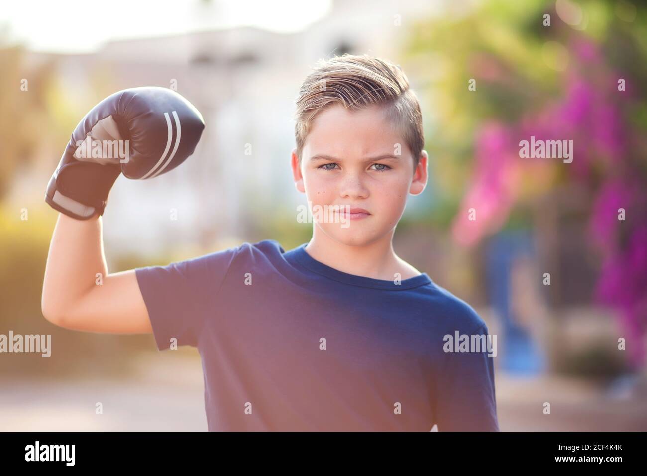 Enfant garçon avec des gants de boxe montrant un extérieur résistant. Concept de l'enfance, des loisirs et de la santé Banque D'Images