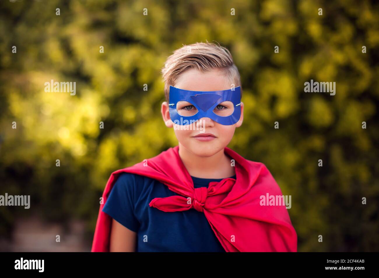 Super-héros garçon enfant sur fond vert en extérieur. Enfance, succès et concept de puissance Banque D'Images